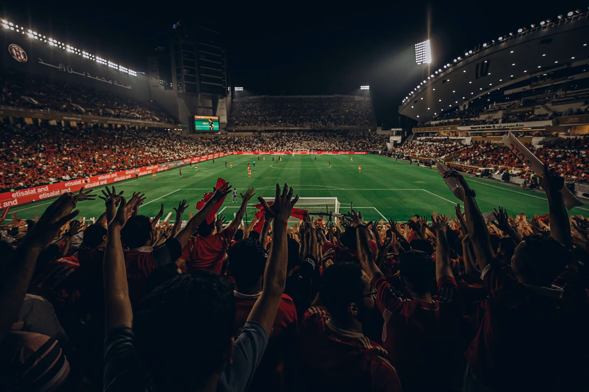 อัฒจันทร์แน่นขนัดยามค่ำคืน แฟนบอลชูมือเชียร์ในเกมฟุตบอลระดับเมเจอร์